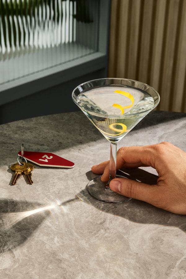Man picking up a Martini with keys on the table