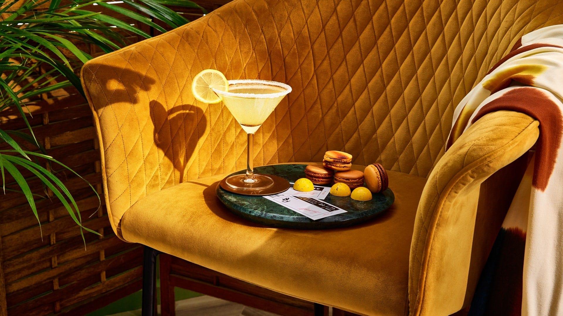 A lemondrop martini on a chair with a hand shadow coming in