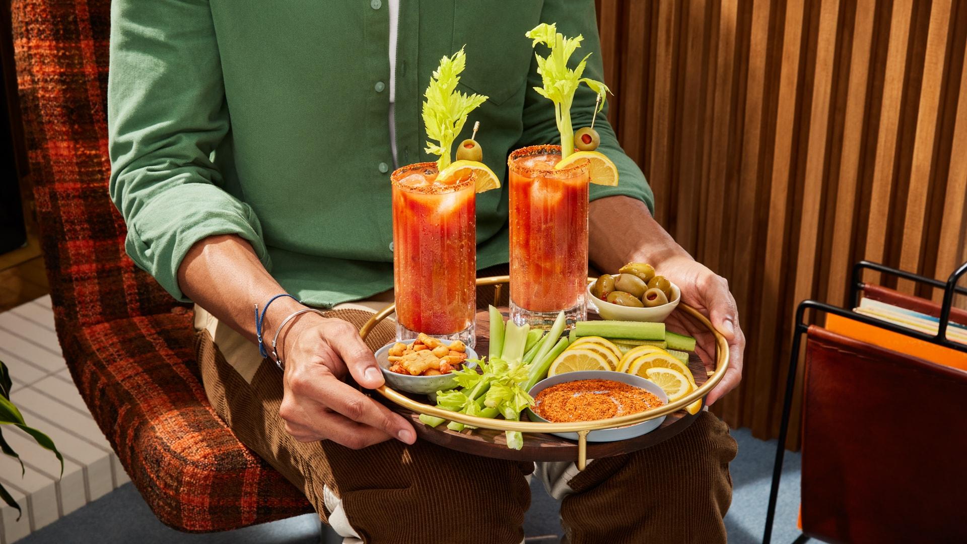 Two Bloody Mary’s on a tray accompanied by the ingredient