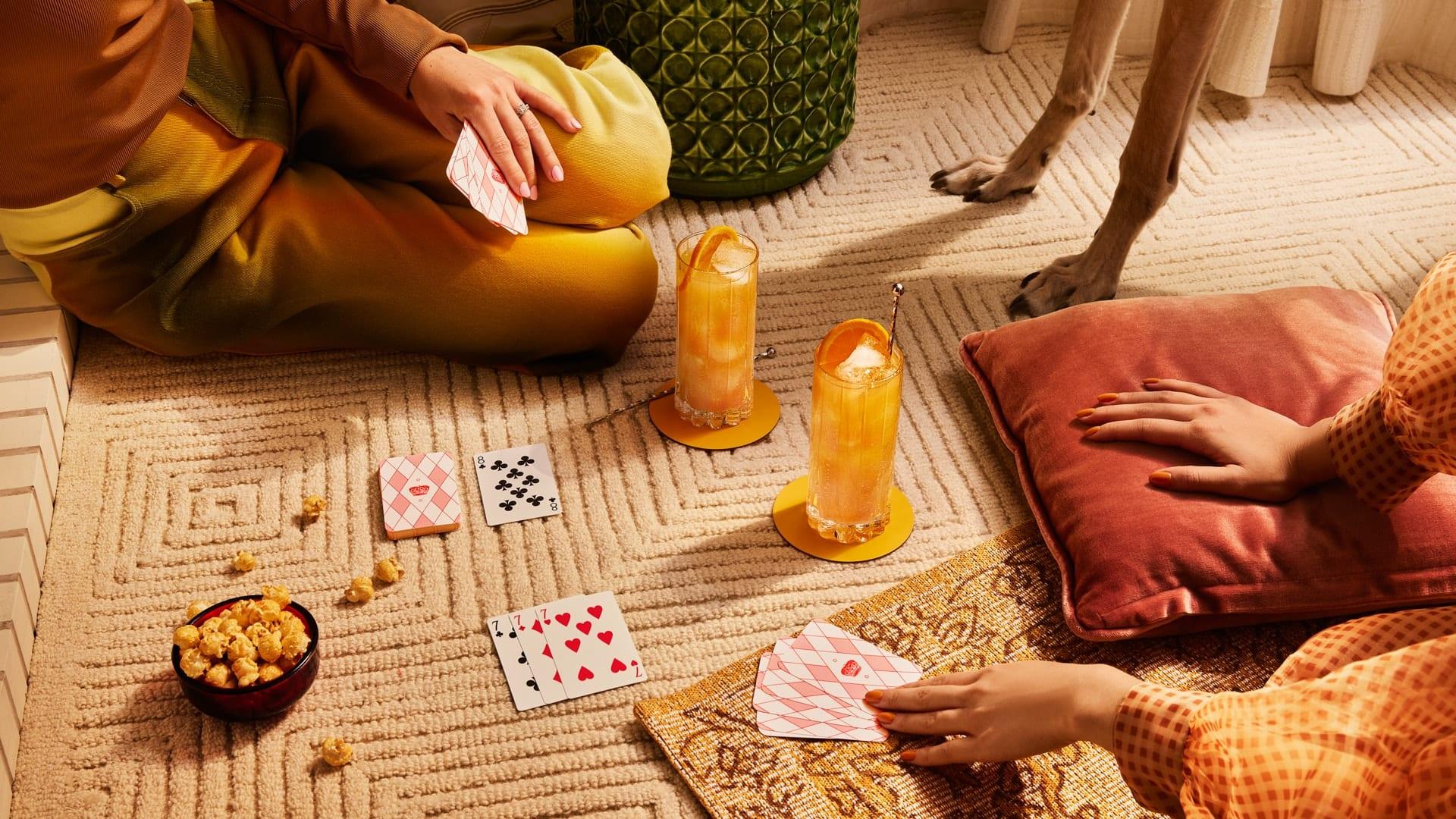 Two people and a dog playing cards with Smirnoff Vanilla Dream cocktails