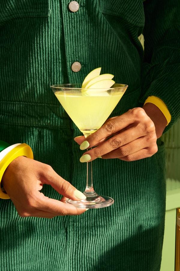 A person holding a Smirnoff Green Apple Martini
