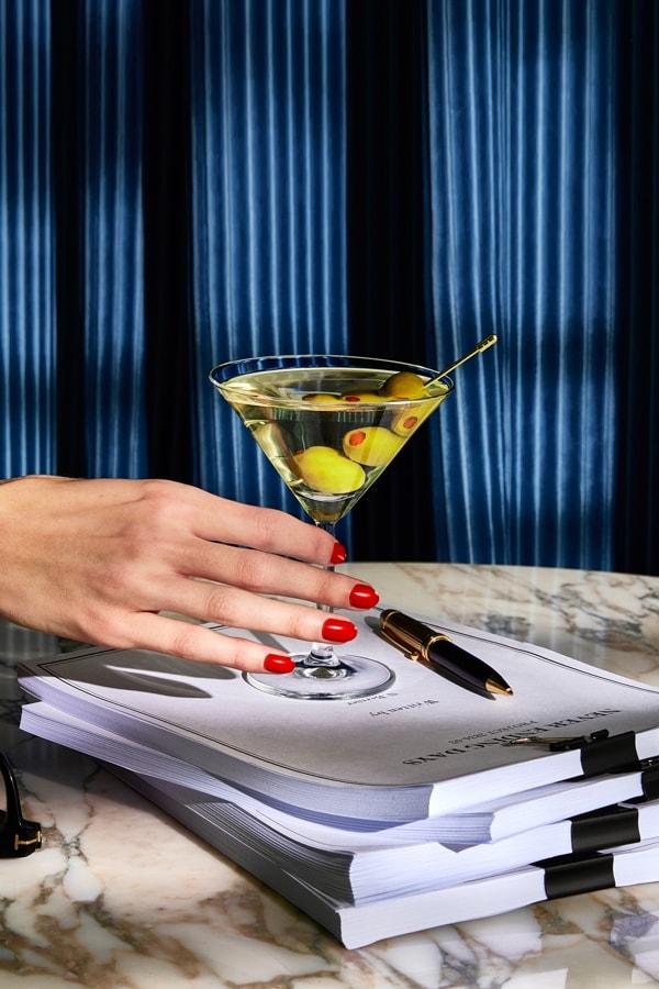 A Smirnoff Dirty Martini cocktail sitting on a stack of papers